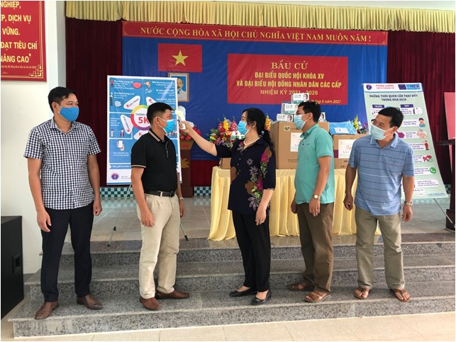 Ảnh 2: TS Đào Thị Ngọc Lan hướng dẫn cách đo thân nhiệt cho các thành viên Ban chỉ đạo phòng chống dịch covid-19 tại xã Cảm Ân